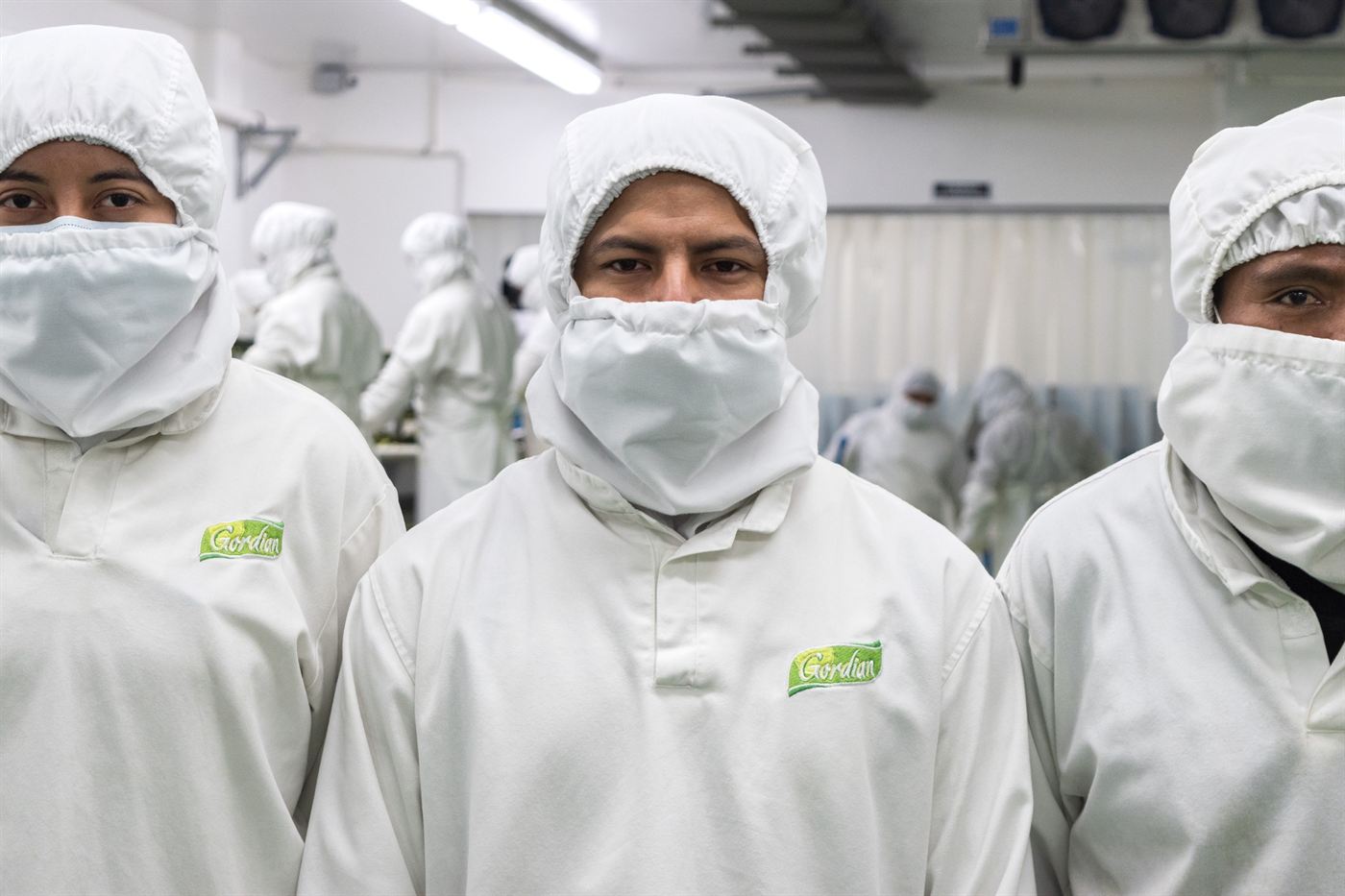 Gordian plant workers in full whites with the company logo on the chest