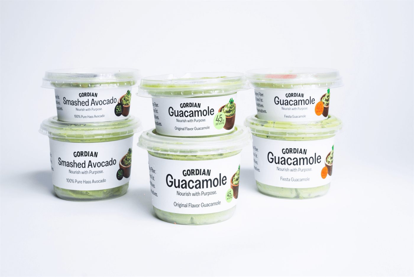 Six cups of Gordian guacamole and smashed avocado on a white surface