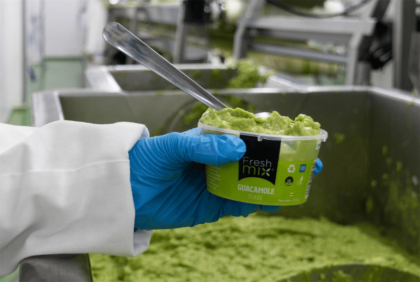 An operator filling a customer-branded guacamole cup on the line