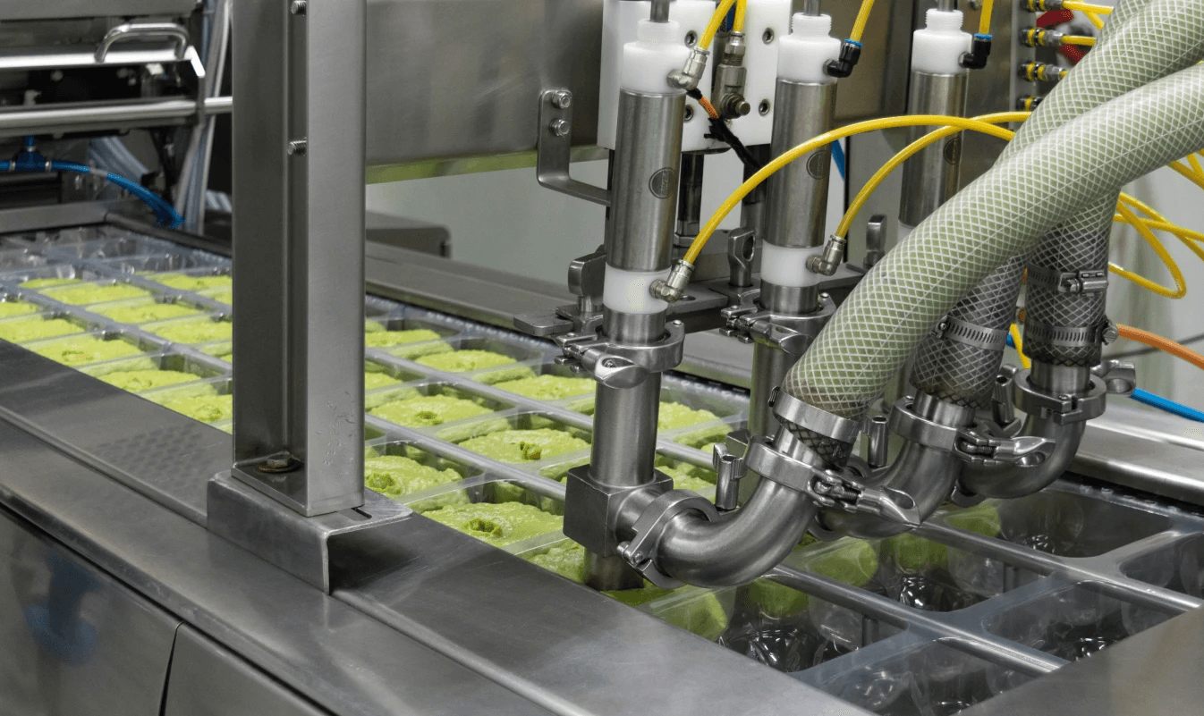 The filling machine dosing smashed avocado into trays
