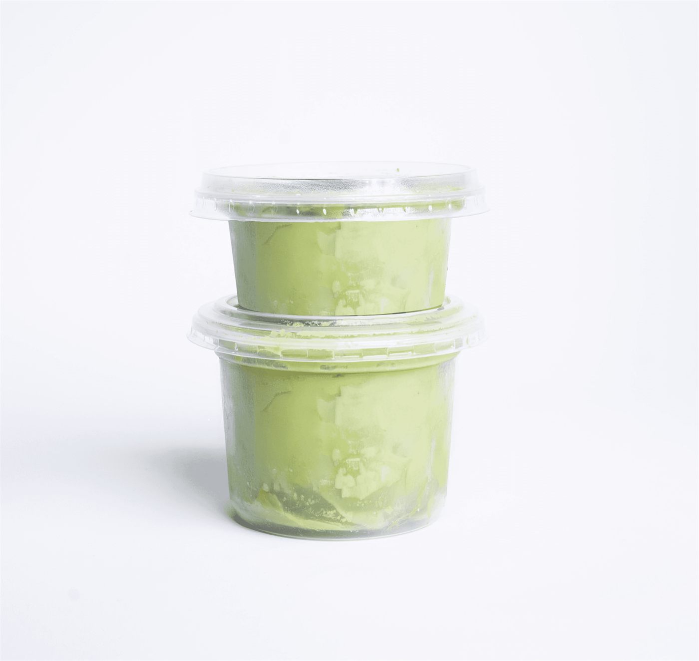 Two cups of Gordian guacamole stacked on a white surface
