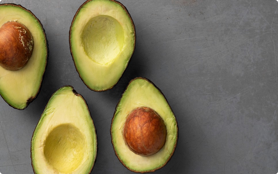 Four halves of Hass avocado laid out on a grey stone surface